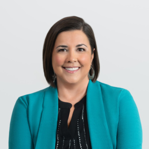 a headshot of carrie downey with clarity co wearing a black outfit and green jacket